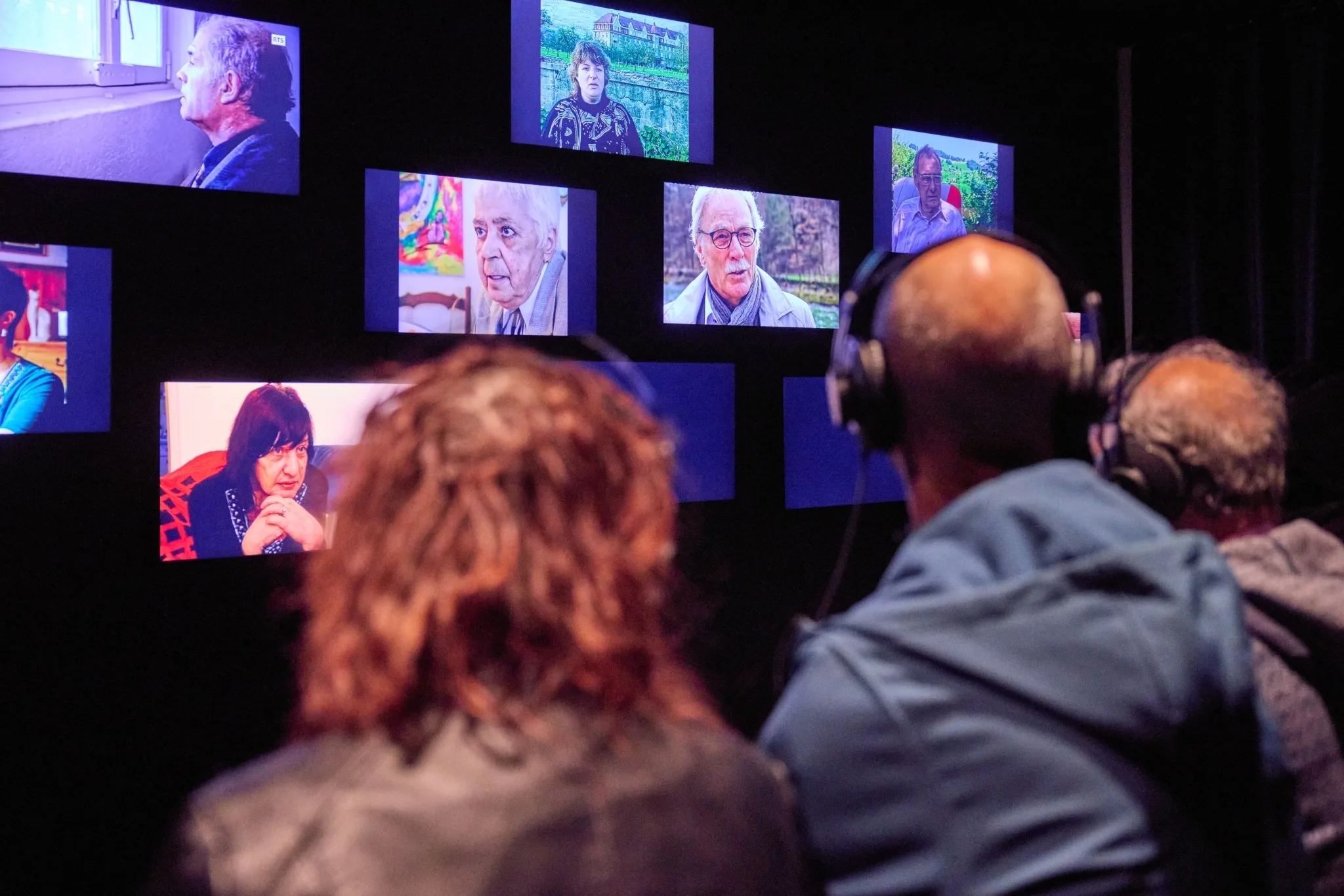 Drei Personen sitzen vor Bildschirmen in der Ausstellung.
