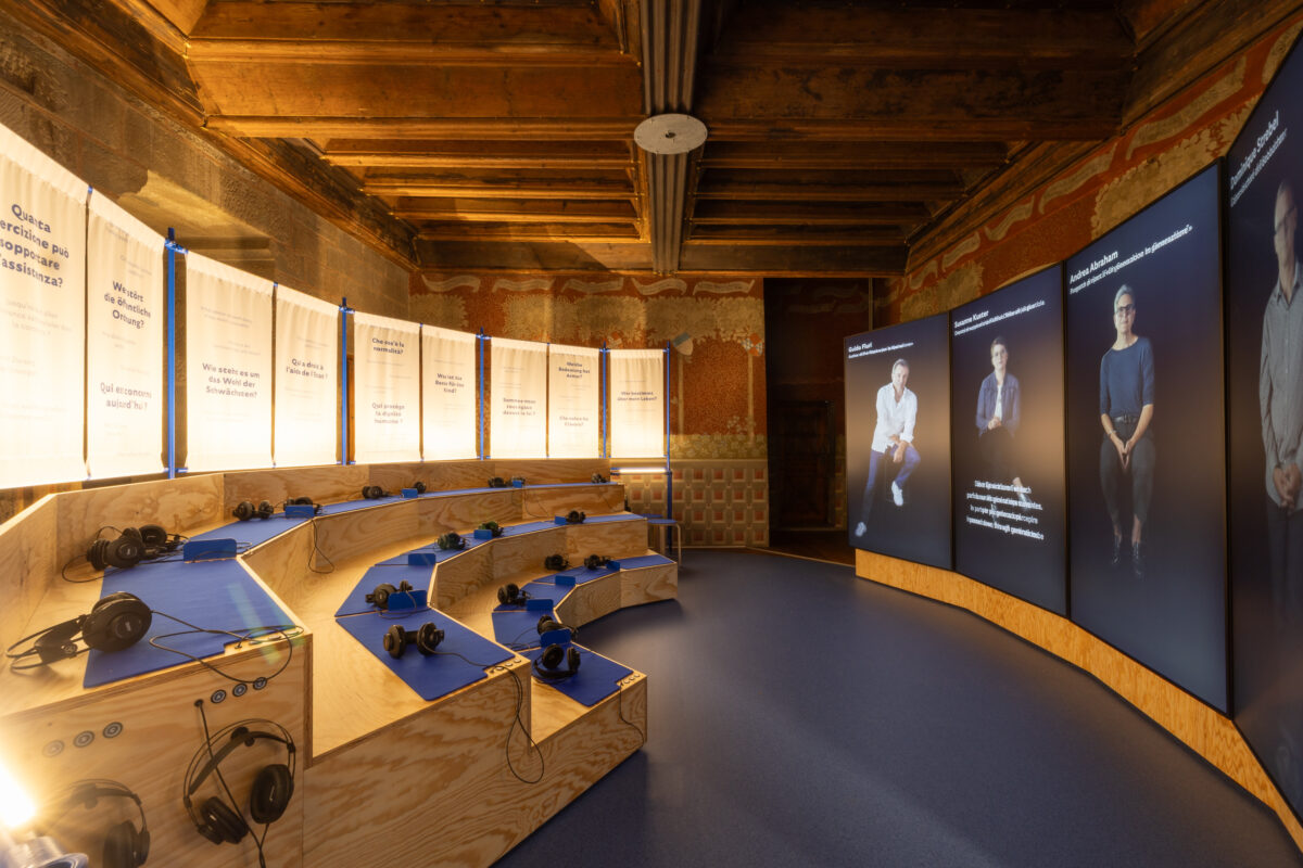 Ein Forum mit Kopfhörern und vis-a-vis Bildschirme mit Menschen